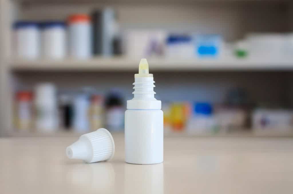 A bottle of opened eye drops on a pharmacy counter.