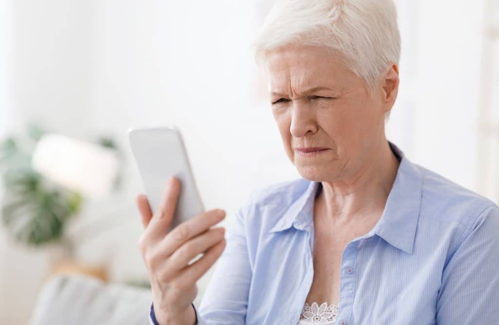 A woman squints at her phone, struggling to see well with blurred vision.